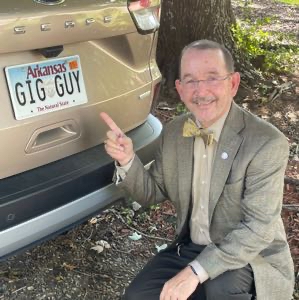 Tim Brown next to his car with license plate "Gig Guy" named after his grocery delivery business.